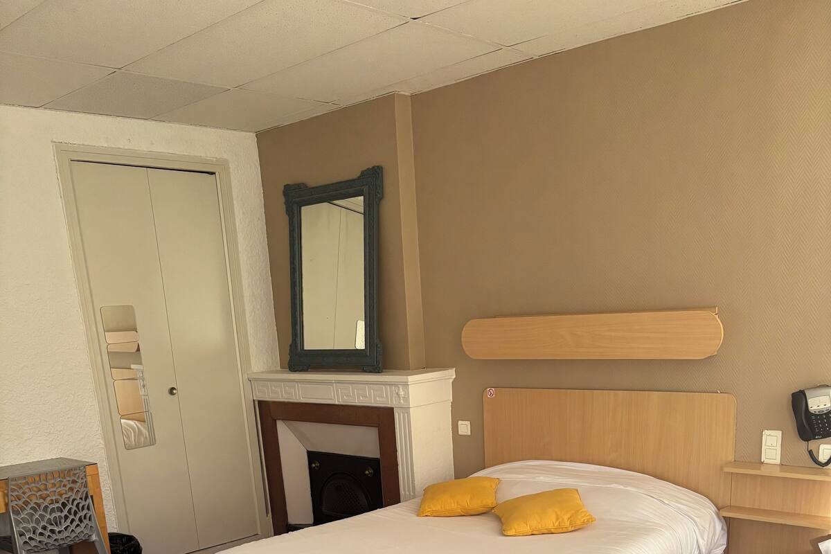 A hotel room with two beds, a wooden headboard, a mirror, a telephone, and a small table.