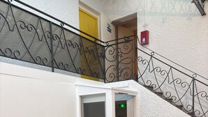 Pasillo de hotel con una escalera, un pequeño rincón de descanso y una puerta marcada con el número 2.