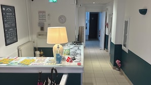 Zona de recepción de un hotel con mostrador, reloj, directorio y felpudo.