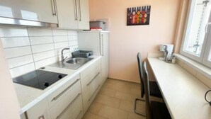 Uma cozinha pequena com armários brancos, uma pia e uma janela.