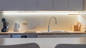 Een moderne keuken met een ingebouwde vaatwasser, een koffiezetapparaat en een messenblok.