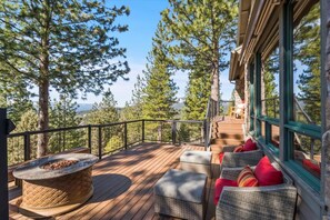 A wooden deck with wicker furniture and a stone fire pit, surrounded by trees and overlooking a mountainous landscape. - Mountaintop Cabin Hot Tub Views Family Golf (Portola)