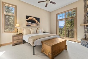 Quarto com uma cama grande, mesa de cabeceira, luminária, pintura e lareira de pedra.