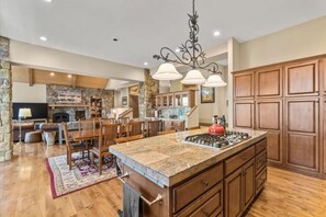 A spacious kitchen with a large island, stone accents, wooden cabinetry, and a stone fireplace. - Mountaintop Cabin Hot Tub Views Family Golf (Portola)