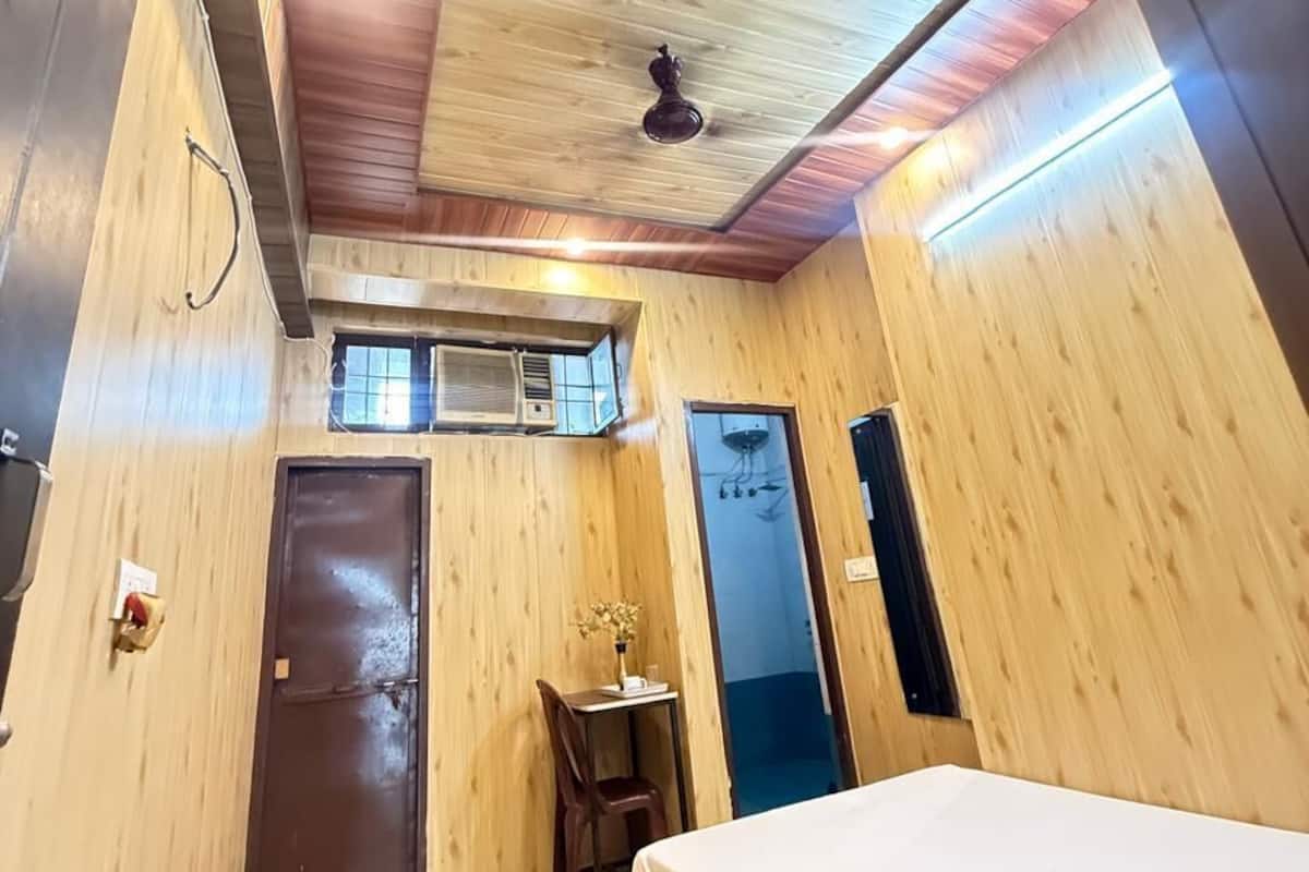 A room with wooden walls, a ceiling fan, a bed, a desk, and a window.
