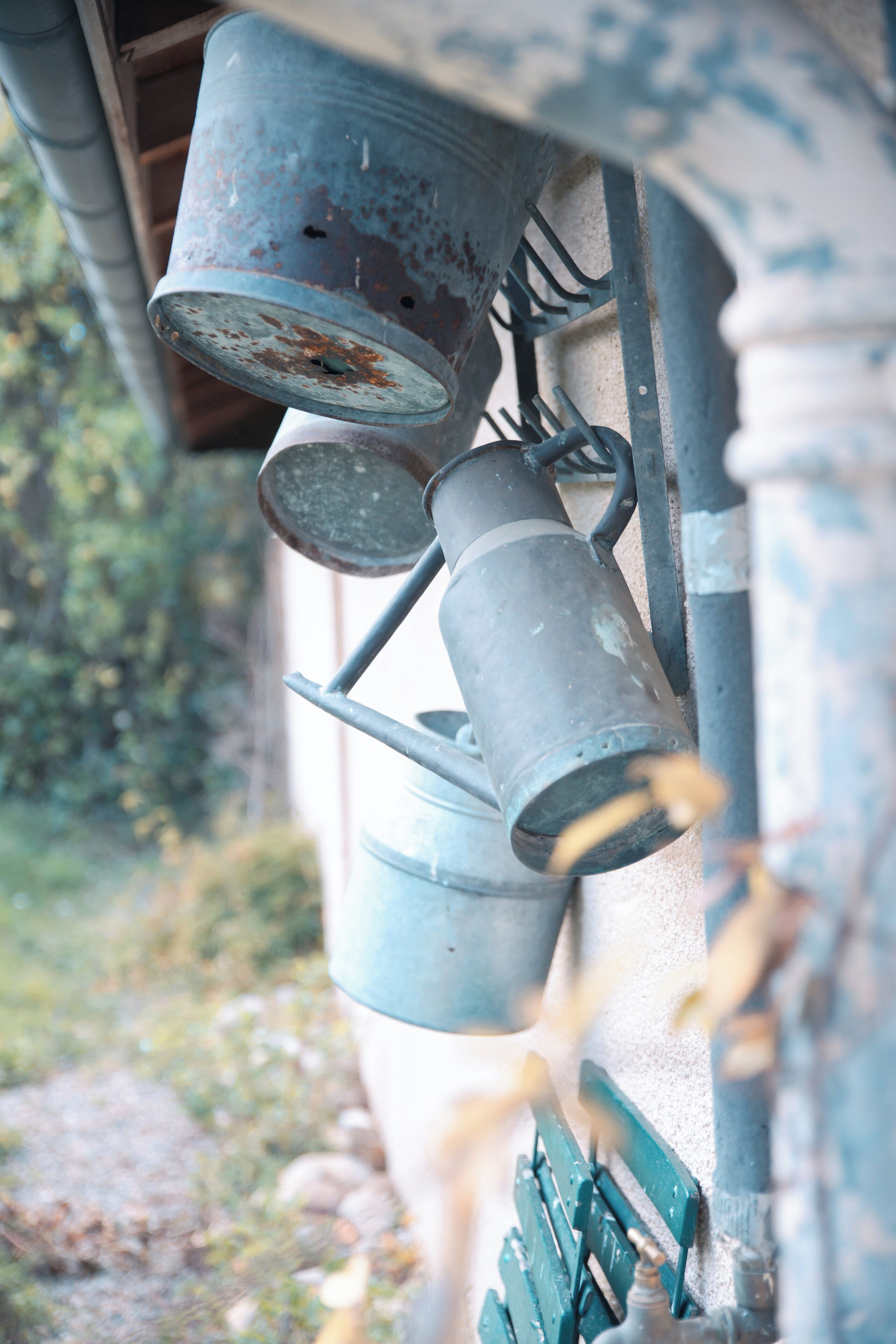 A series of metal buckets mounted on a wall, likely used for collecting rainwater.