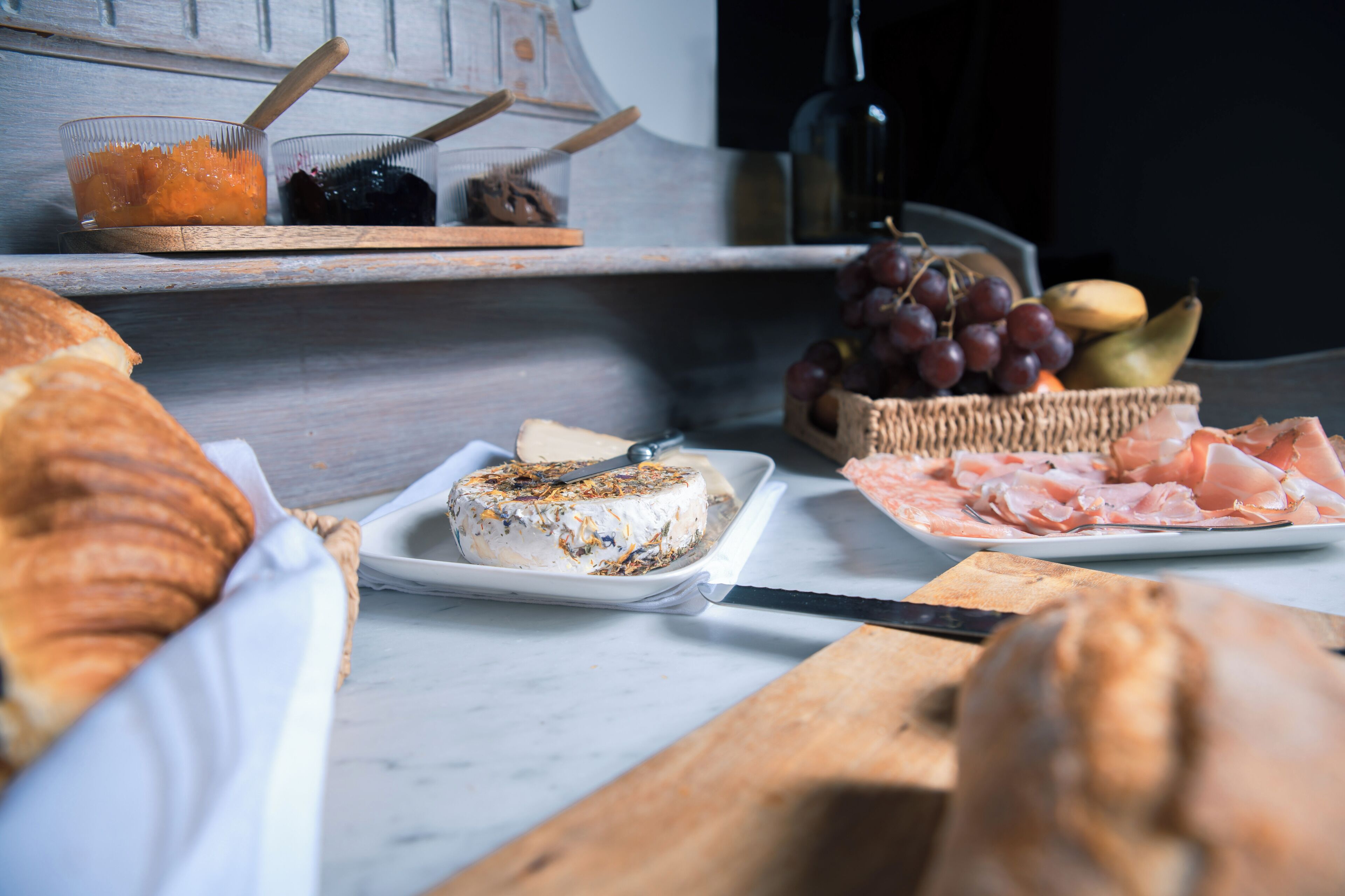 Una mesa con diversos alimentos, incluyendo queso, pan y frutas.