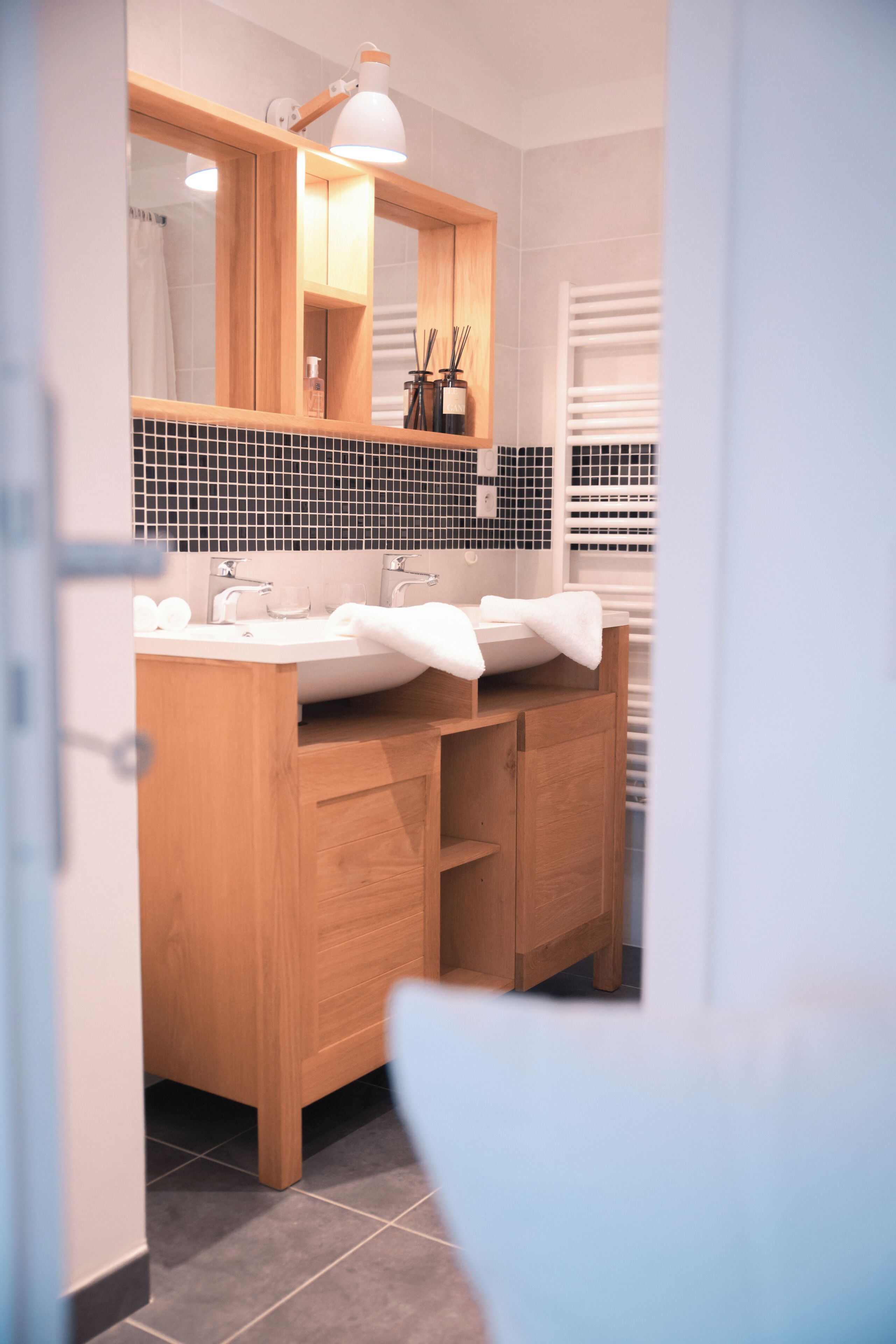 A modern bathroom with a wooden vanity, dual sinks, and a large mirror.