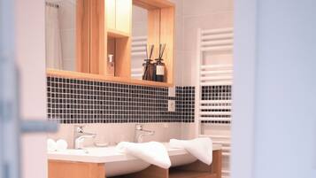 A modern bathroom with a wooden vanity, dual sinks, and a large mirror.