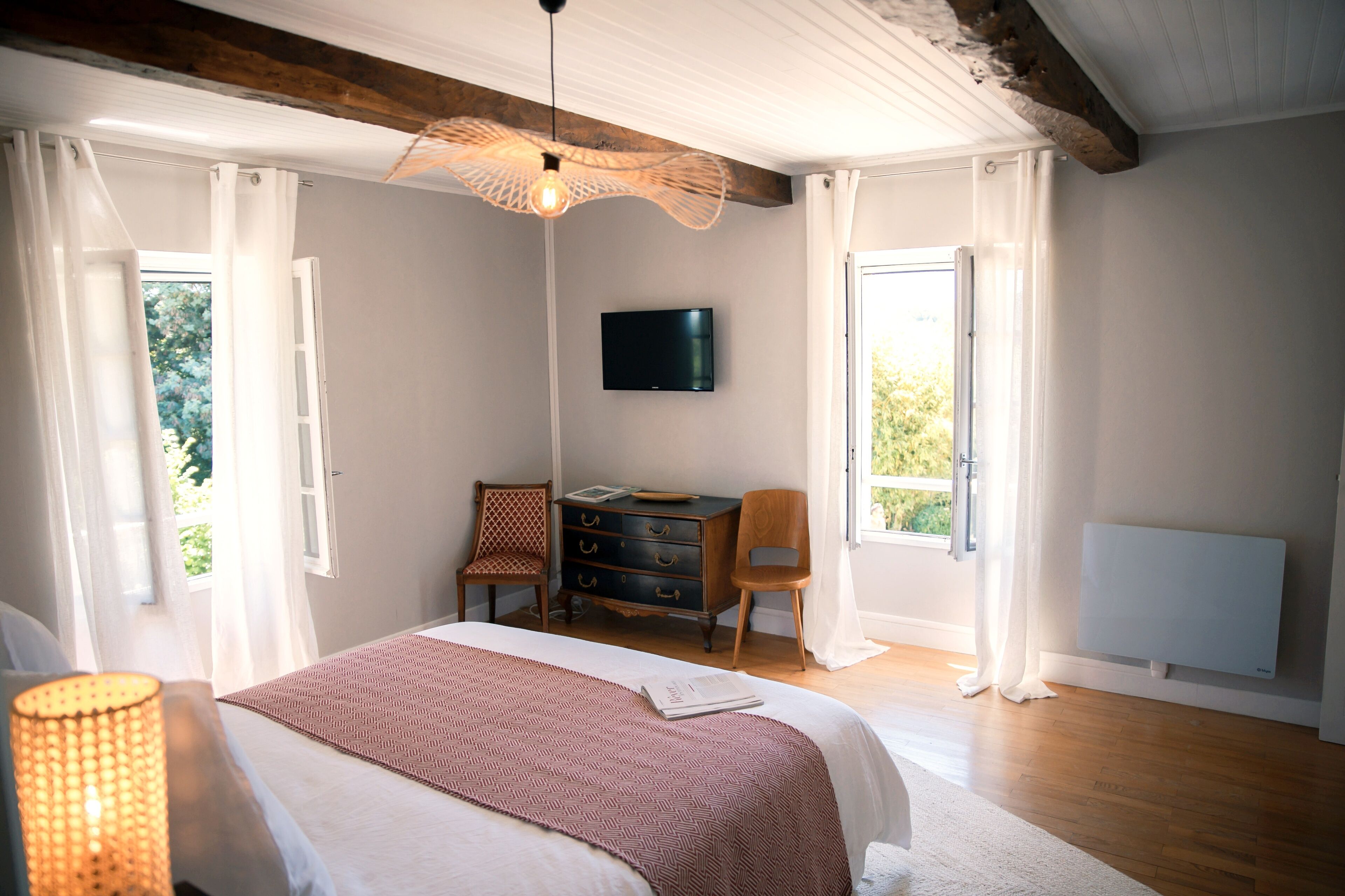 Une chambre à coucher avec un lit, un bureau, une chaise, une télévision et une fenêtre avec des rideaux.