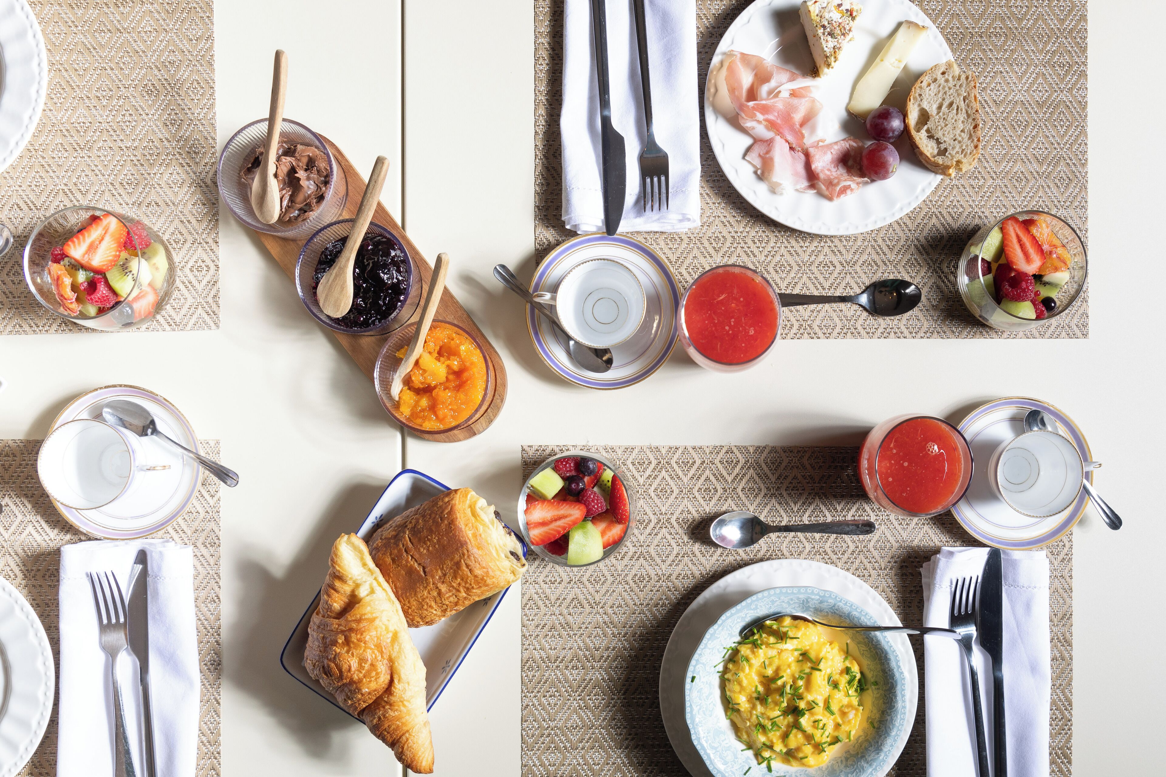 A breakfast setting with various dishes including fruits, pastries, and a bowl of soup.