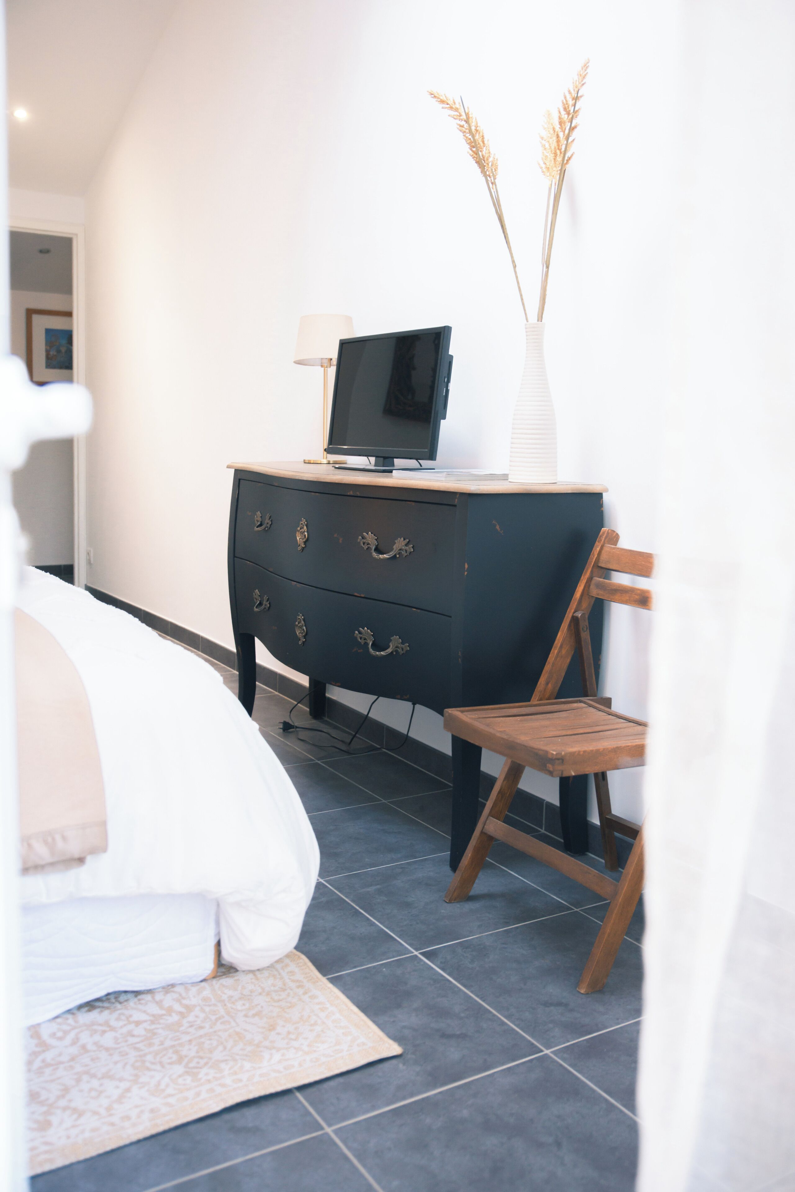 A bedroom with a bed, a dresser, a chair, and a TV on the dresser.