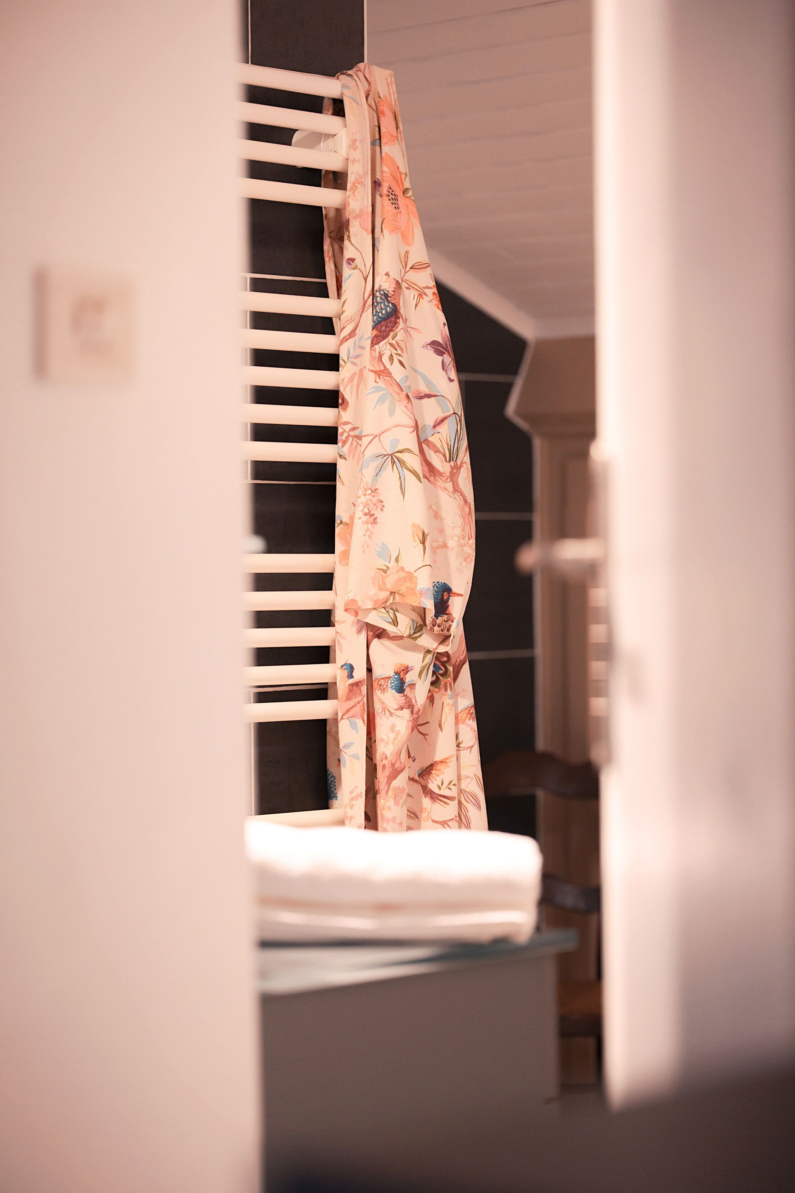 A bathroom with a white bathtub, a shower curtain with a floral pattern, and a towel rack.