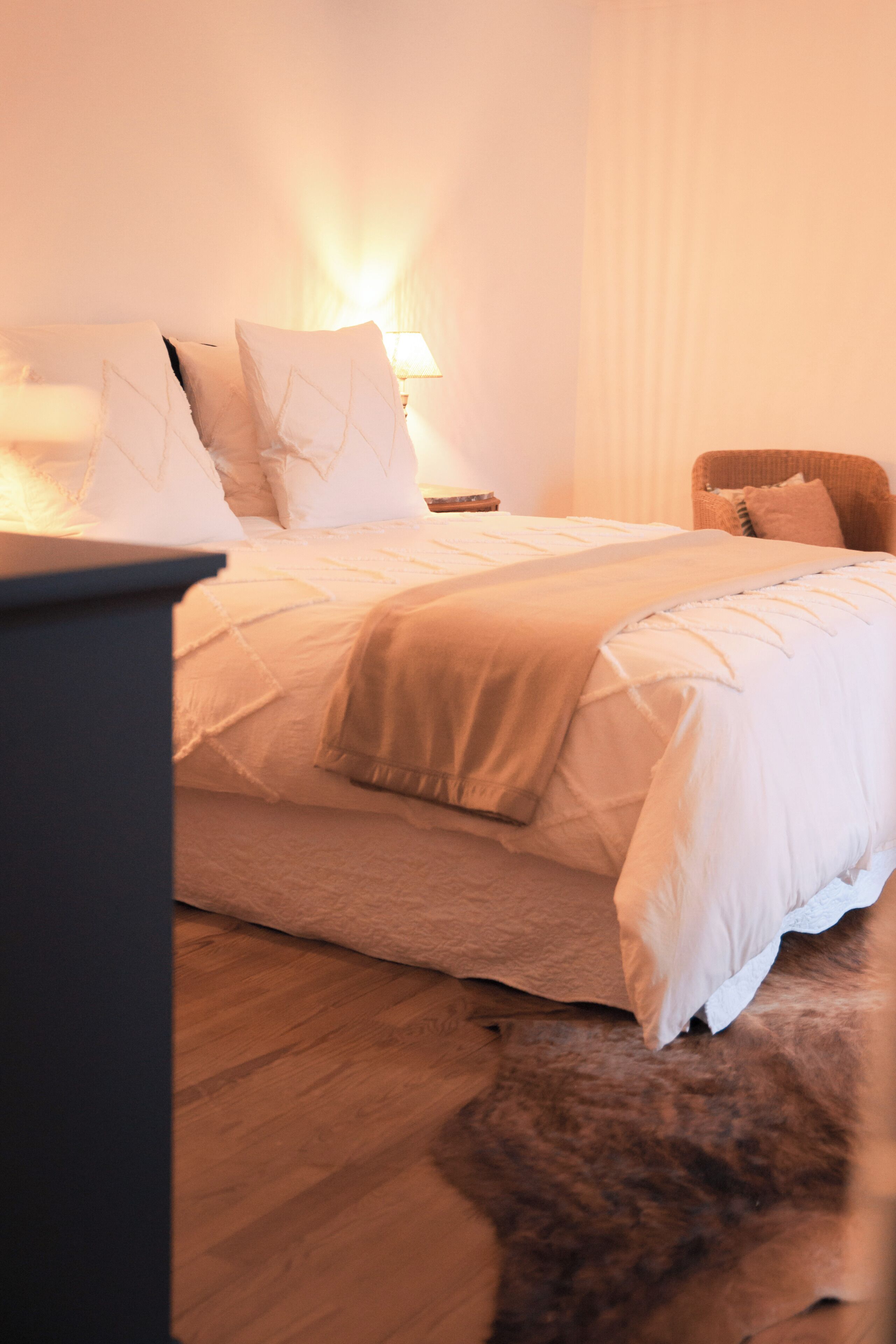 A bedroom with a bed, a chair, a lamp, and a rug.