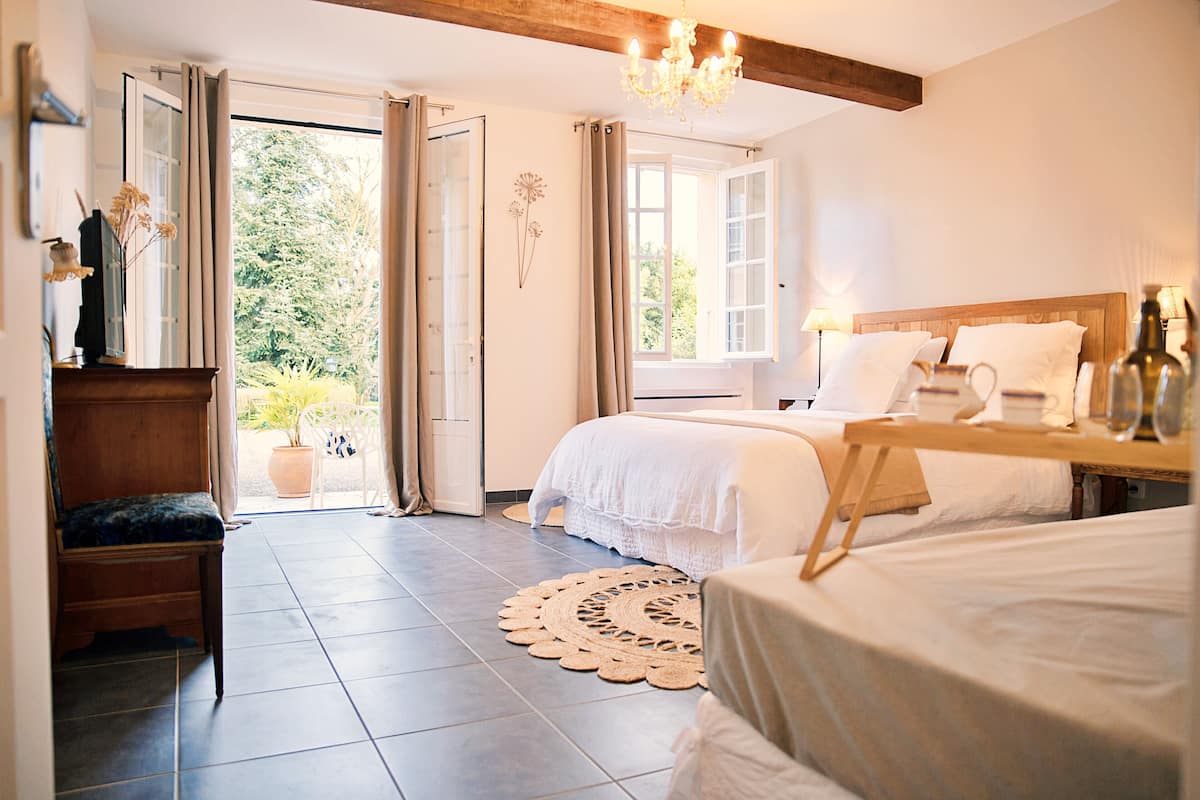 A bedroom with a bed, bedside table, and a view of the outdoors.