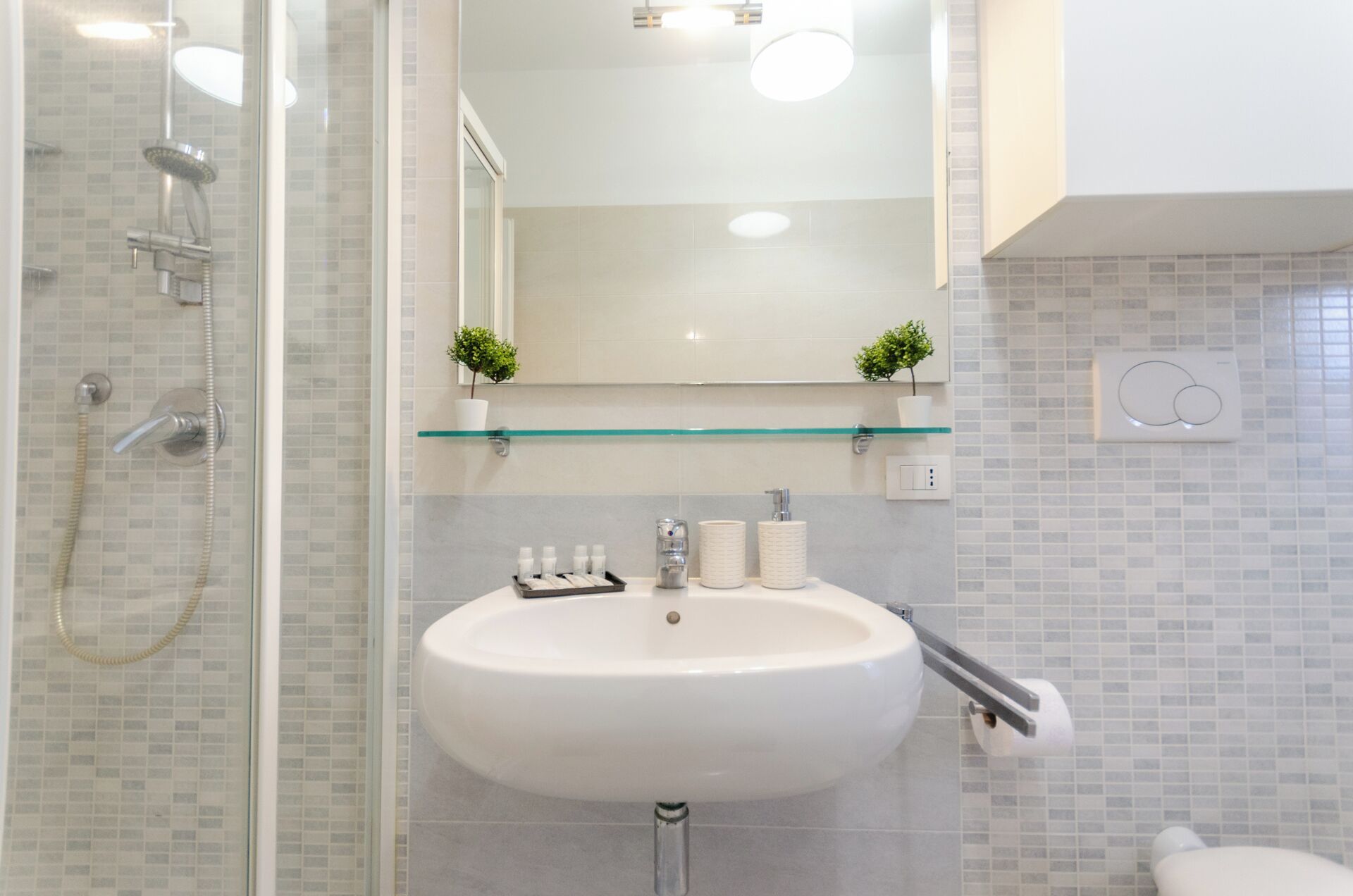 A modern bathroom with a glass shower enclosure, a white sink, and a mirror above.