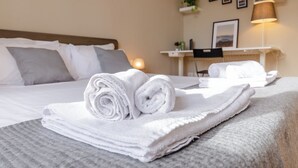 A neatly made bed with rolled white towels, a bedside table with a lamp, and a wall with framed pictures. - VivimiHome-Apartment near Milano Central (Milan)