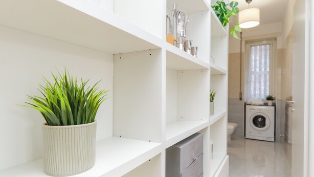 A clean, modern bathroom with white fixtures, a potted plant, and a visible washing machine in the background. - VivimiHome-Apartment near Milano Central (Milan)