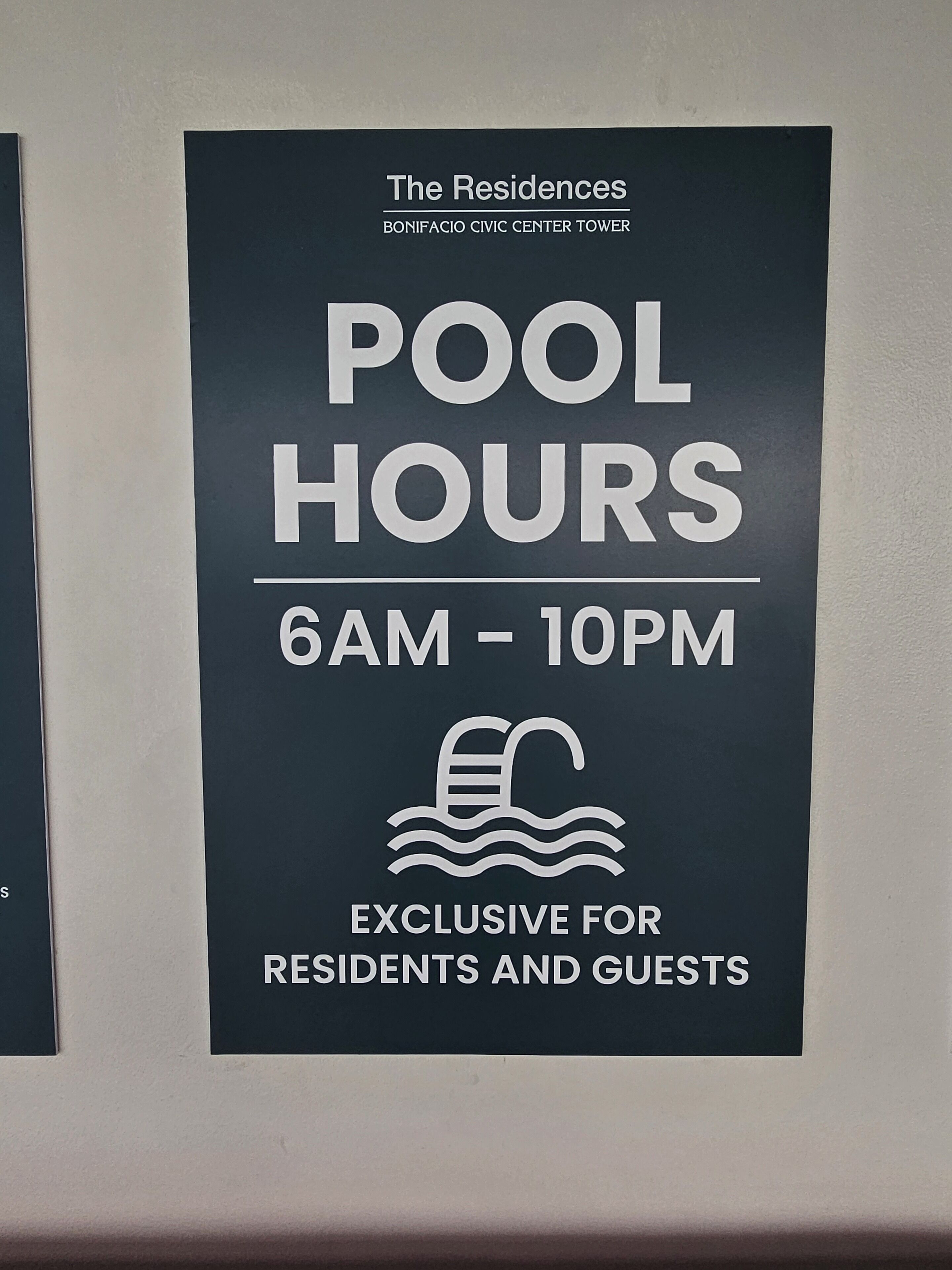 A sign indicating pool hours at The Residences, BONIFACIO CIVIC CENTER TOWER, from 6 AM to 10 PM, exclusive for residents and guests.