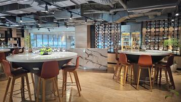 A modern bar area with round tables and bar stools, a wine rack, and a marble countertop.
