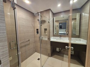 A modern bathroom with a glass-enclosed shower, a vanity with a mirror, and a sink. - The Residences at BCCT by Stays PH (Taguig)