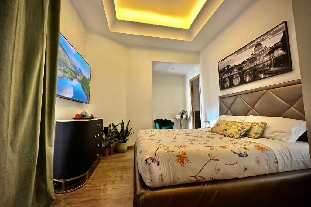 A modern hotel room with a large bed, a flat-screen TV, a dark-colored dresser, and a painting on the wall.