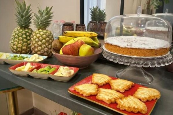 A buffet table with a variety of food items including fruits, a pie, and pastries.