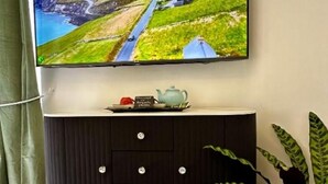 A television mounted on a wall above a dark wooden cabinet with drawers.