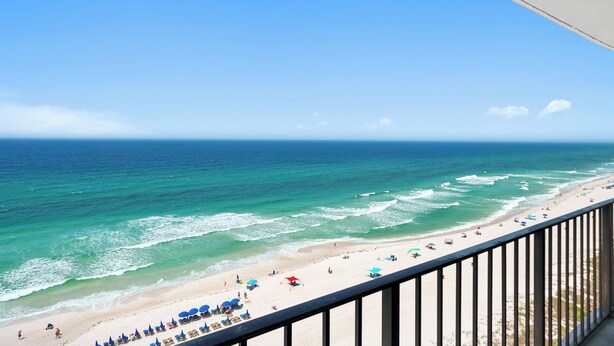 A beach with clear blue water, a sandy shore, and a balcony with a railing. - Unbeatable Views in this 3BR 3BA Condo at the Watercrest w/Beach Chairs! (Panama City Beach)
