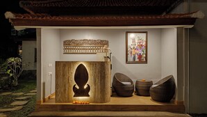 A wooden structure with a carved design, a framed picture, and two wicker chairs. - Ray Guest House  (Ubud)