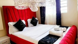 A bed with a red headboard, white bedding, and a canopy. - The Attic Place South B (Nairobi)