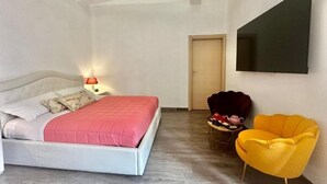 Ein Schlafzimmer mit einem Bett, einem Sessel, einem Fernseher und einer Tür.