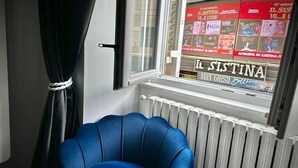 A room with a blue chair, a window with posters, and a radiator.