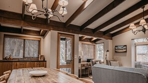 A cozy dining area with a wooden table and chairs, a sofa, and a chandelier. - Bundaleer - Woodridge (Woodridge)