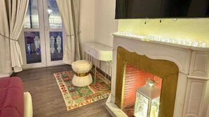 Una sala de estar con chimenea, un televisor montado en la pared y un tapete estampado en el suelo.