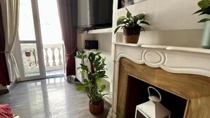 Una sala de estar con chimenea, televisor y plantas en macetas.