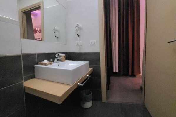 Un baño moderno con un lavamanos, espejo y toallero blancos.