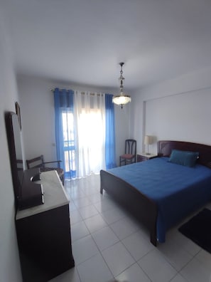 A hotel room with a bed, a desk, a chair, a lamp, and a chandelier. - Nice Lagos 3 Bedrooms Balcony Flat (Lagos)