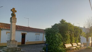 A cobblestone courtyard with a white building, a stone monument, and a bench. - Ferreira Alentejo Terrace Villa (Ferreira do Alentejo)