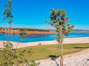 A clear view of a beach with a pool, surrounded by greenery and a clear blue sky.