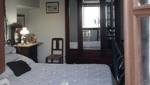A bedroom with a bed, a chair, a dresser, a mirror, and a window. - Ferreira Alentejo Terrace Villa (Ferreira do Alentejo)