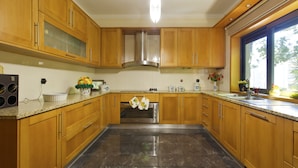 A kitchen with wooden cabinets, a stainless steel oven, and a window with a view of greenery.