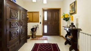 A hallway with a wooden cabinet, a door, a vase with flowers, and a radiator.