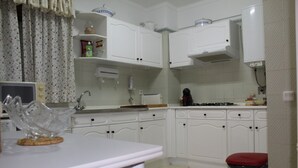 Una cocina con armarios blancos, un microondas, una estufa y un cubo de basura.