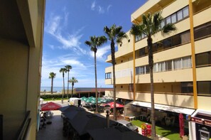 A hotel courtyard with outdoor seating, palm trees, and a view of the ocean. - Espadarte Quarteira Balcony Flat (Loulé)