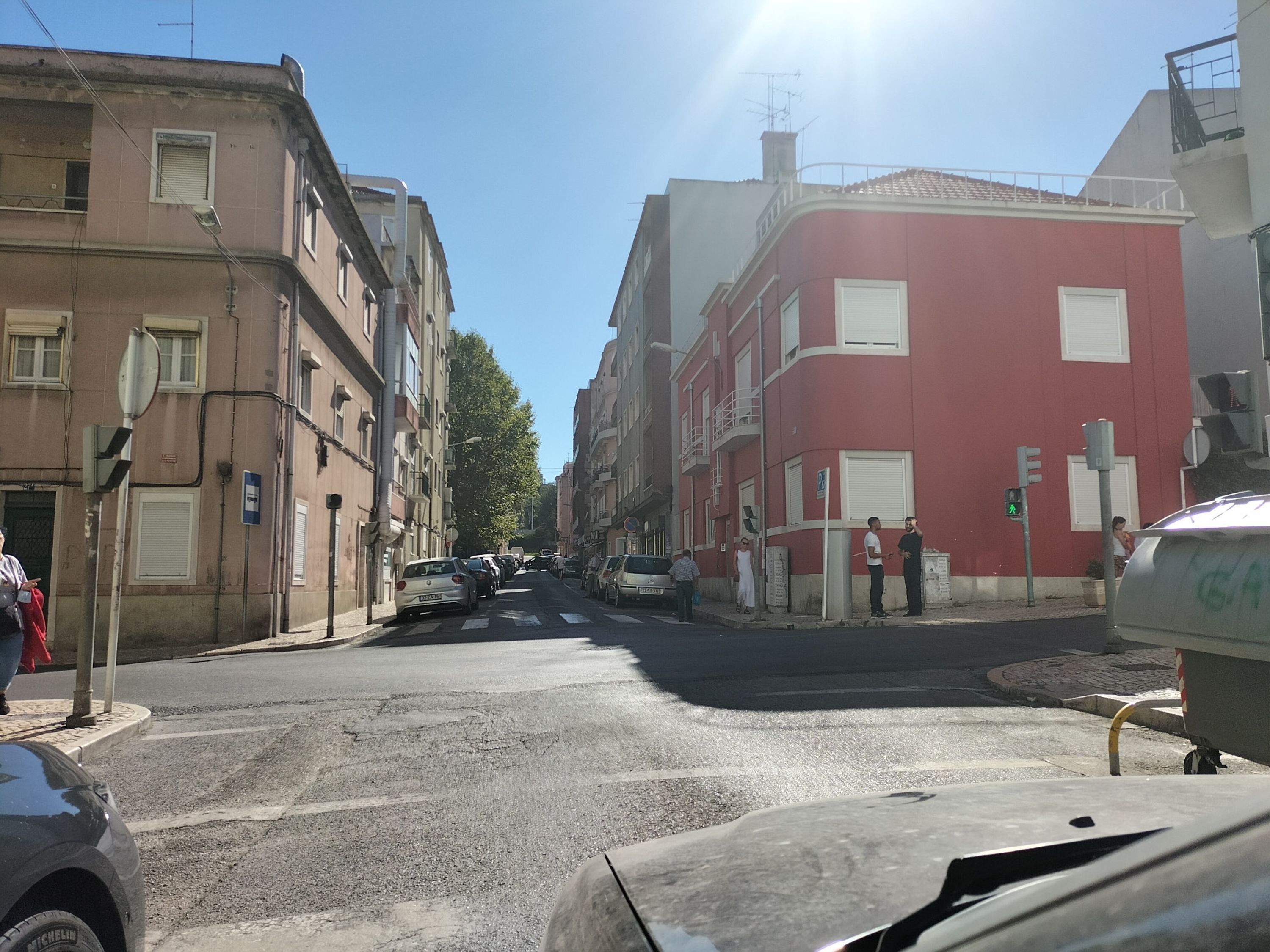 Eine Straße mit Gebäuden, parkenden Autos und einer Fußgängerampel.