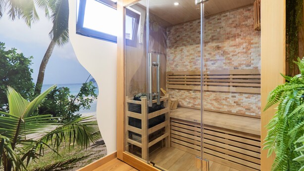 A sauna room with a brick wall, wooden benches, and a glass door. - Quintinha Sao Martinho Luxury 2suites Villa Padrao (Vila do Conde)