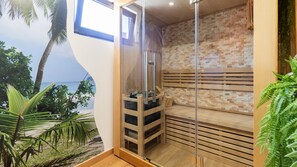 A sauna room with a brick wall, wooden benches, and a glass door.