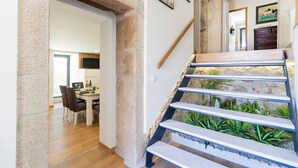 A staircase with a stone wall and a view of a dining area with a table and chairs. - Quintinha Sao Martinho Luxury 2suites Villa Padrao (Vila do Conde)