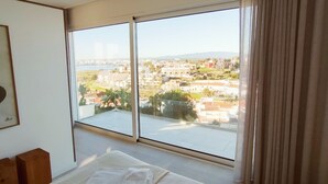 Une chambre d’hôtel avec un grand lit, une vue sur la ville et une fenêtre avec des rideaux.